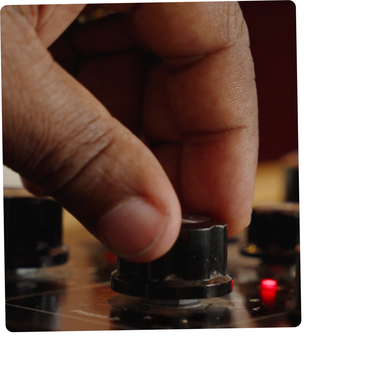 Close-up van een hand die een knop op een mengpaneel bedient.