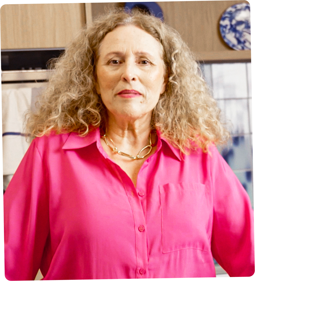 Een vrouw in een roze blouse staat in een keuken.