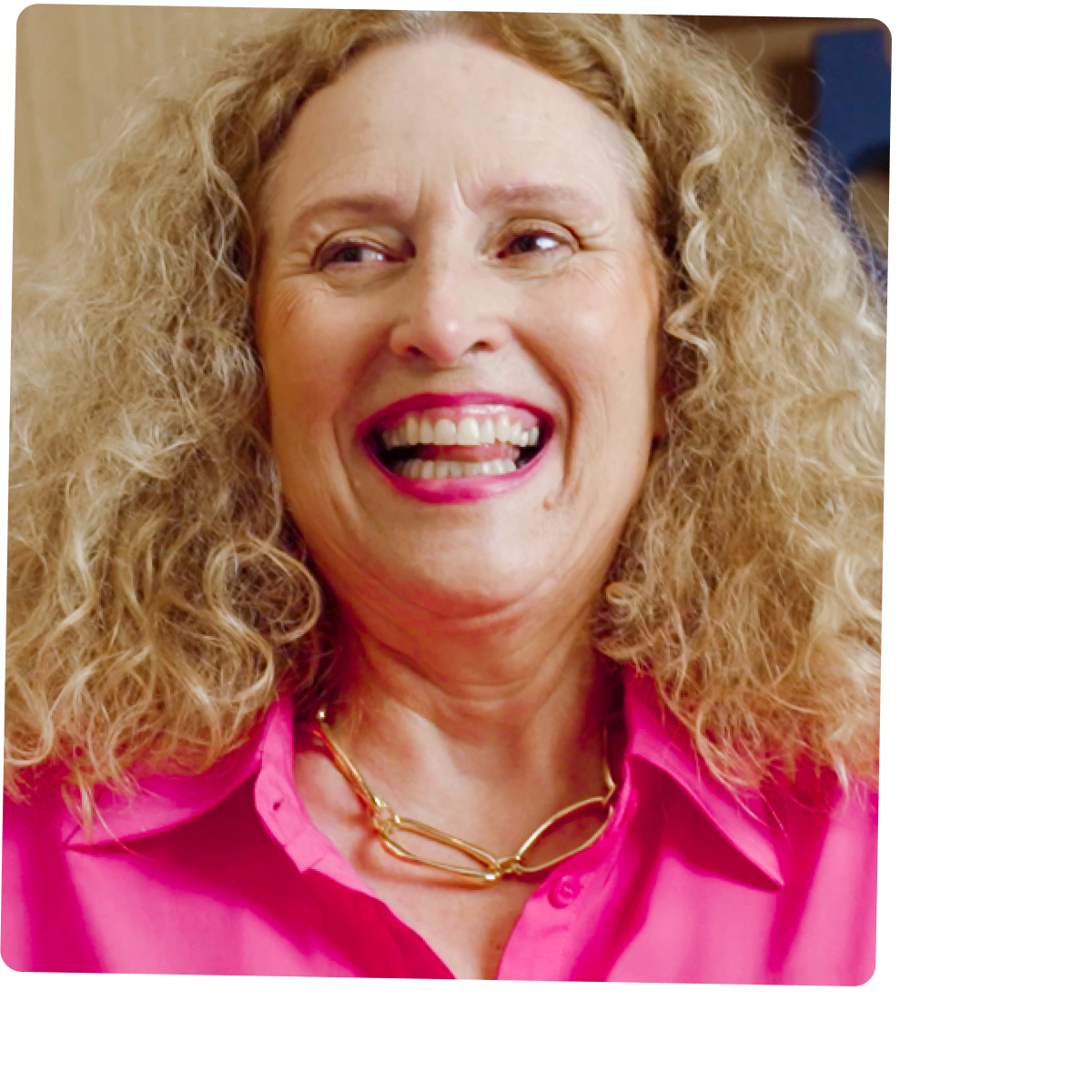 Een vrouw in een roze blouse kijkt opzij en lacht.
